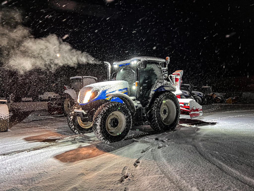 Choreguys New Holland snow tractor in the yard at night during a storm